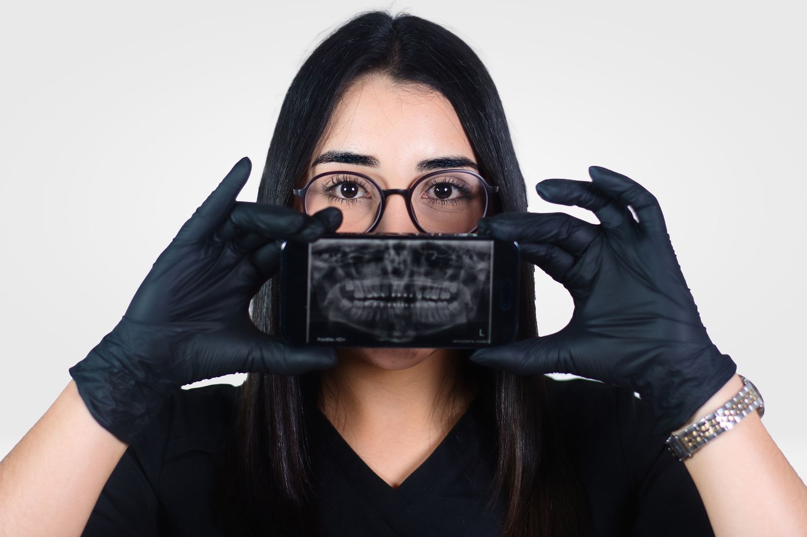 Female dentist holding a dental X-ray displayed on a smartphone, promoting oral health awareness.
